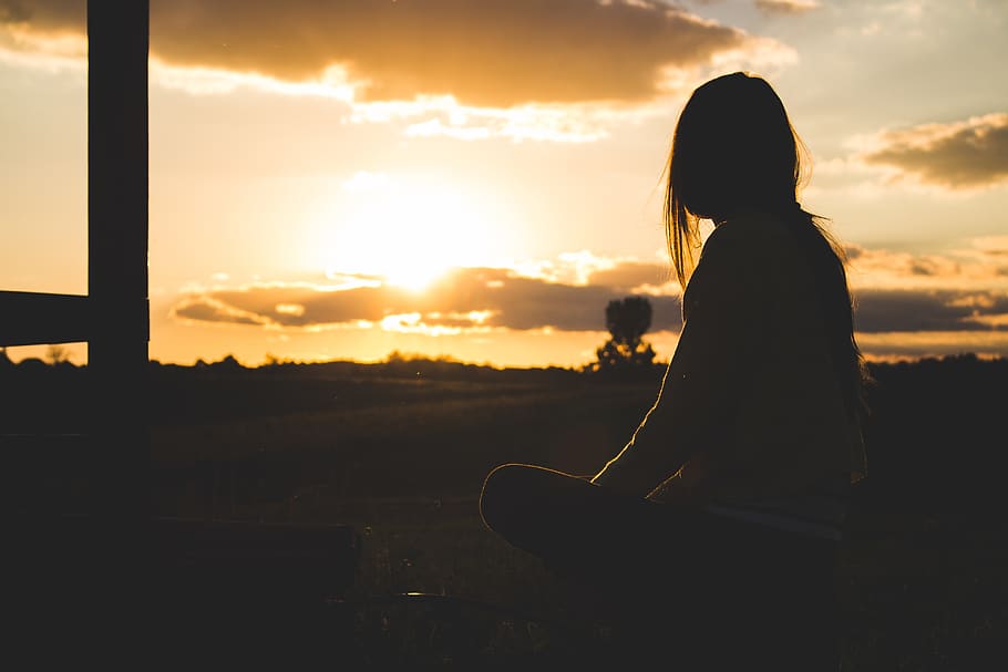 Silhouette Photo of Woman Sitting Near Trees during Golden Hour HD wallpaper