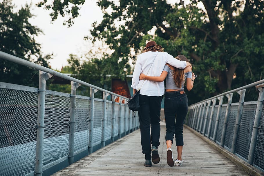 A young caucasian couple with long hair walking on a bridge, 25 to 30 year old