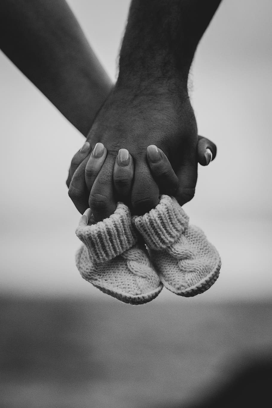 person holding bootees, human body part, close-up, focus on foreground HD wallpaper