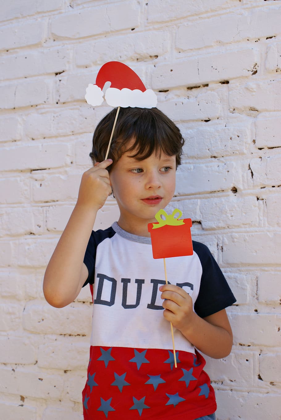 Photo of a Boy Holding Red Christmas Card , adorable, brick wall HD wallpaper