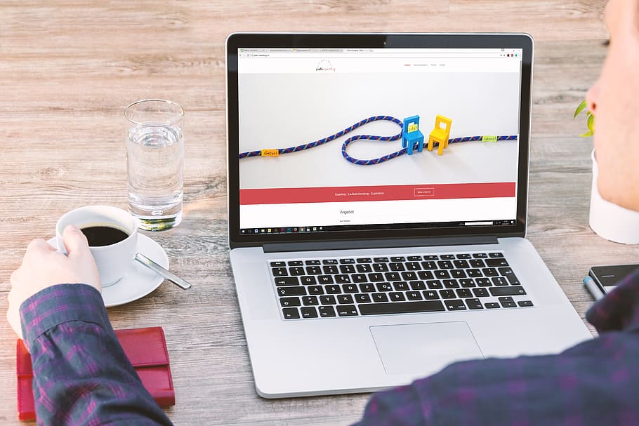 Person Holding a Cup of Coffee Beside Macbook, communication HD wallpaper