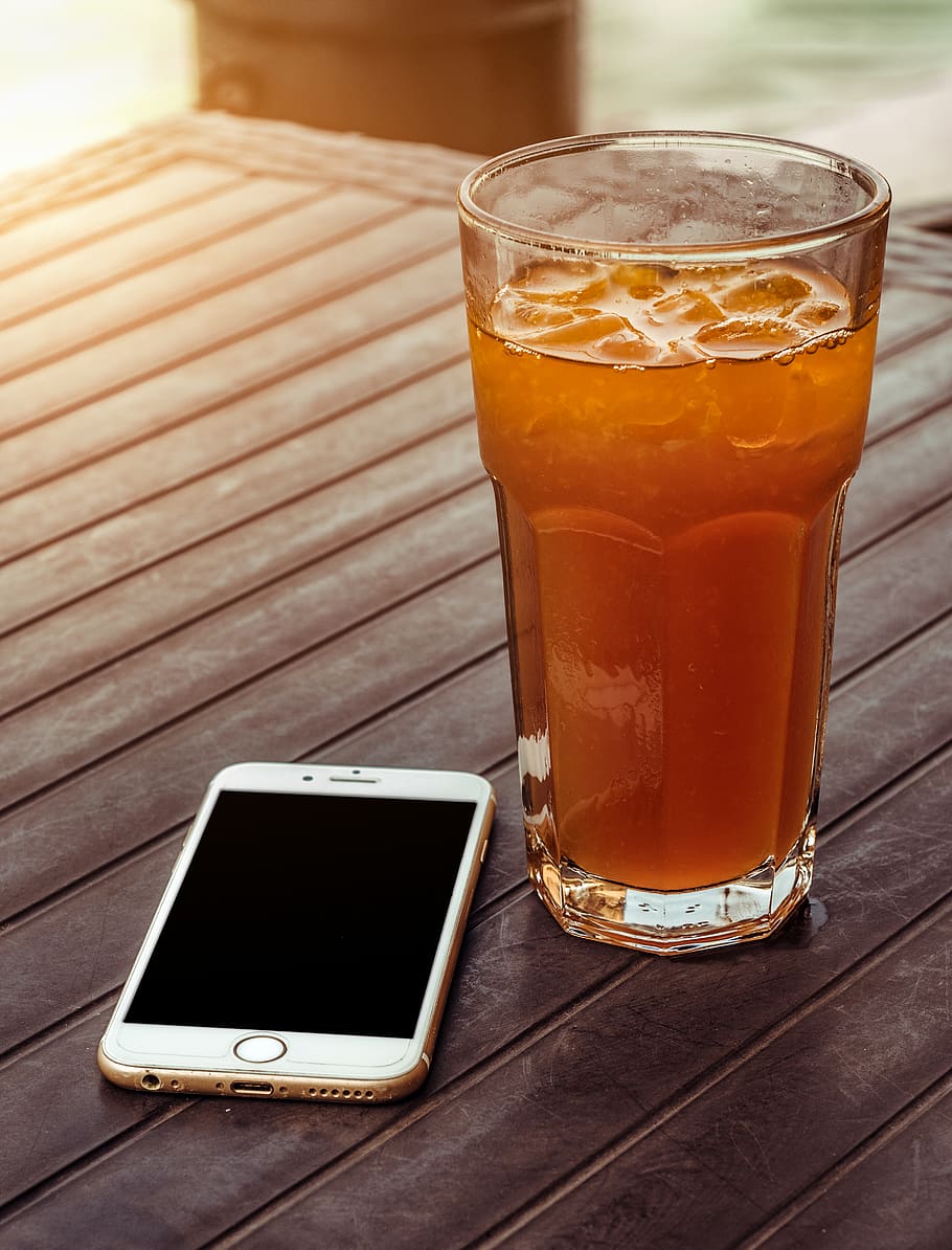 Orange Juice in Clear Drinking Glass Besides Gold Iphone 6 on Brown Wooden Table HD wallpaper