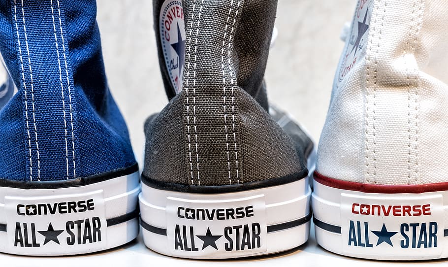 Three Unpaired Black, Blue, and White Converse All Star Sneakers on White Surface