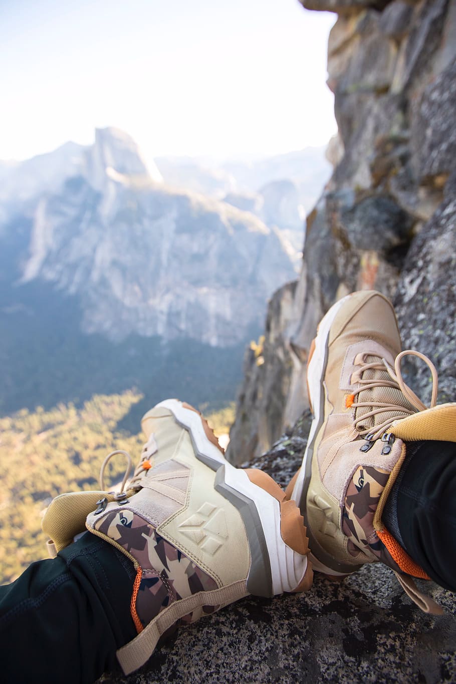 person sitting on rock near gray fault-block mountain, shoe, apparel