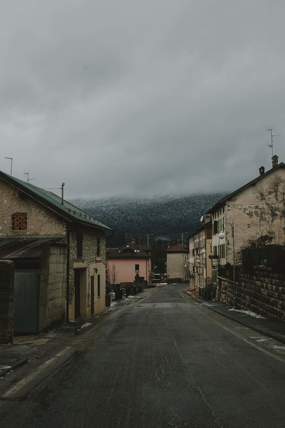 Gray Road Surrounded With Concrete Houses With Background of Dark Clouds HD wallpaper
