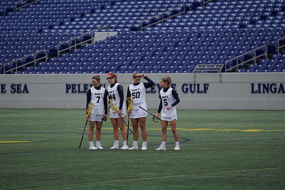 four women holding lacrosse sticks on field during daytime, person