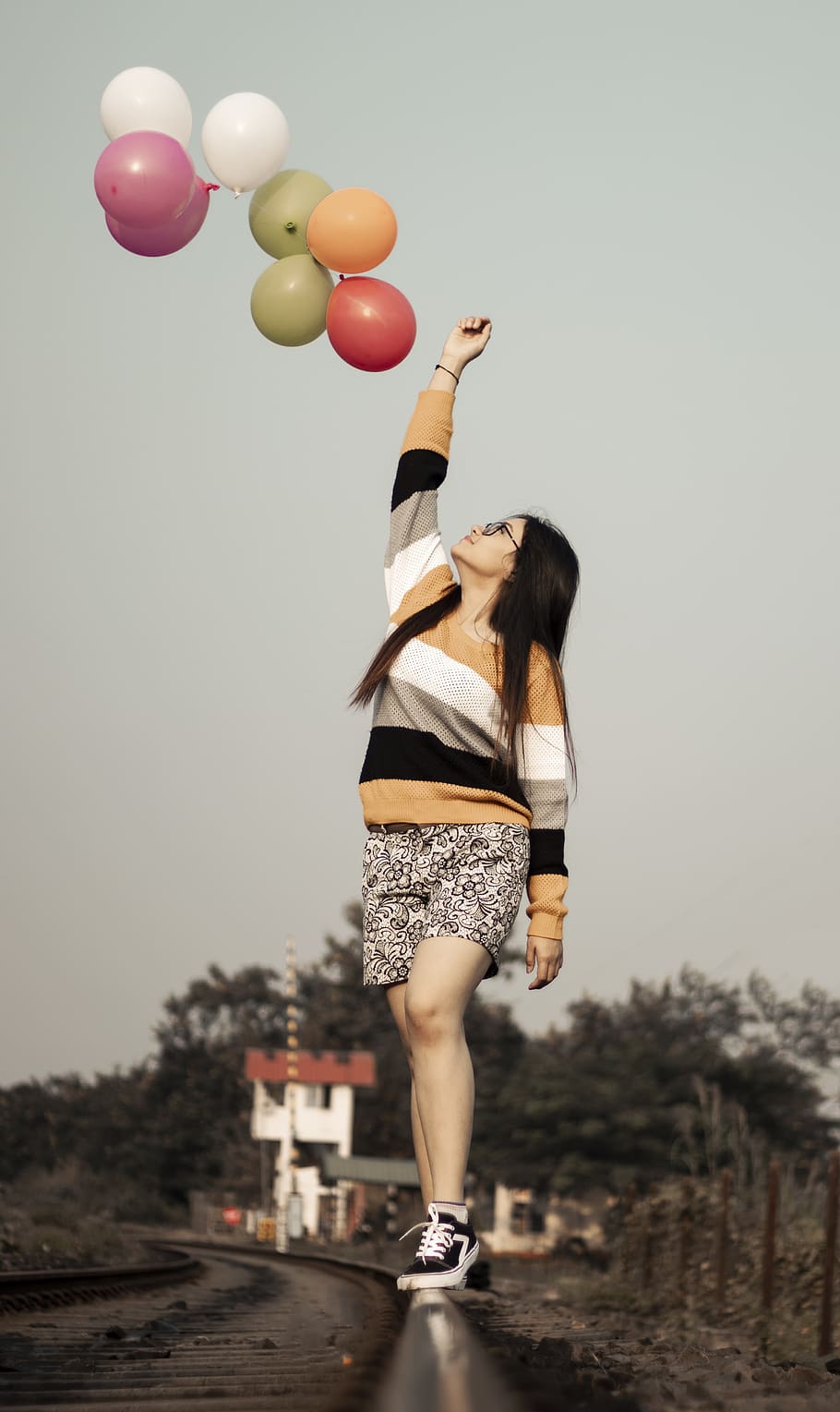 woman on the top of a railway and multicolored balloons, footwear