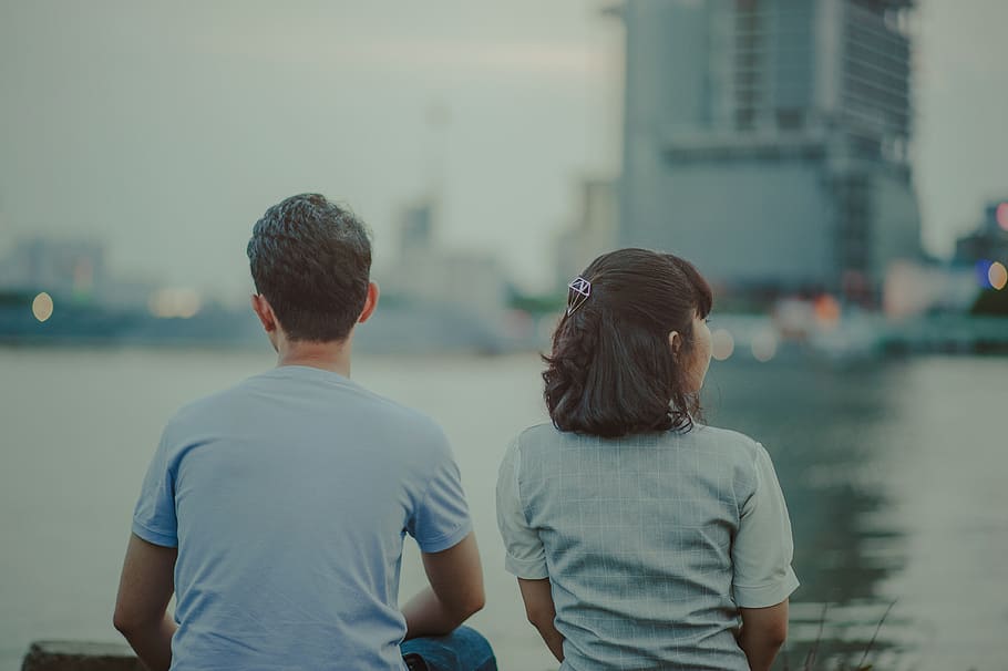 Selective Focus Photography of Man and Woman Watching Body of Water and Concrete Buildings HD wallpaper