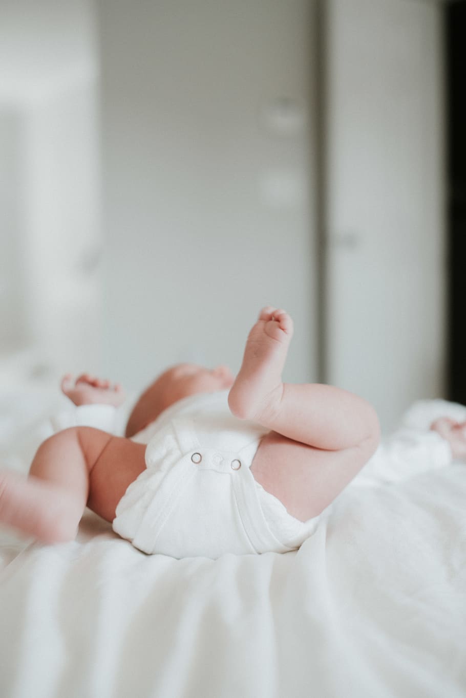 baby's white onesie, person, human, newborn, finger, diaper, furniture