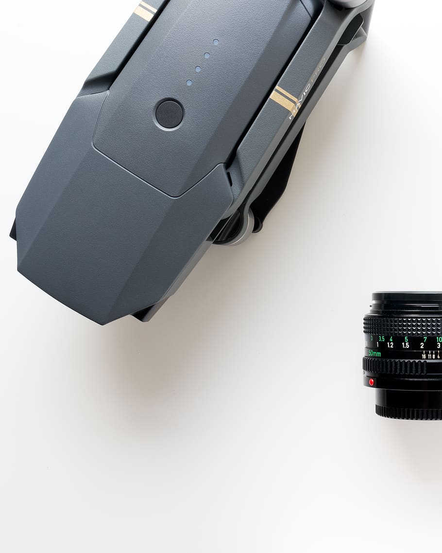 gray DJI Mavic Pro drone beside black zoom lens, connector, electrical device