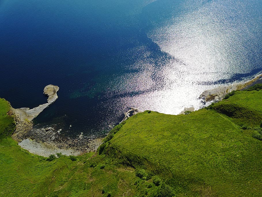 Green Grass Land With Blue Body of Water Below, beach, daylight HD wallpaper