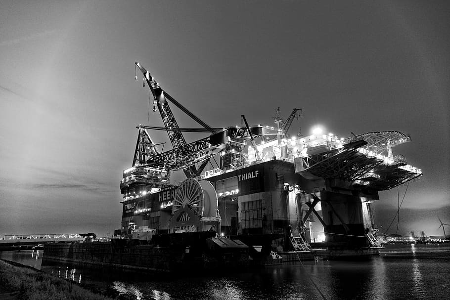 grayscale photography of oil rig, water, illuminated, night, sky