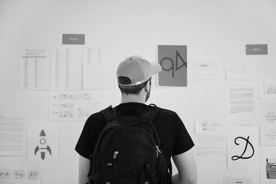 Grayscale Photography of Standing Man Looking on Wall With Pinned Papers HD wallpaper