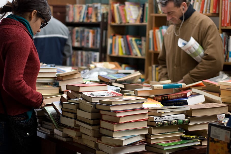 Woman and Man Standing Beside Piles of Books, adult, book store