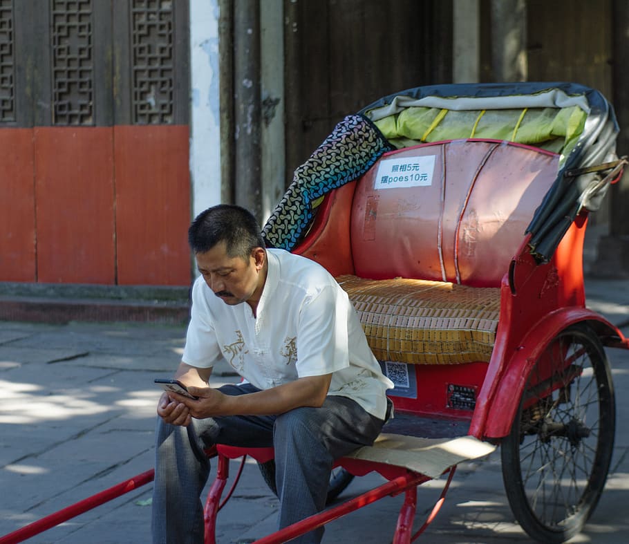 man sitting on red trailer using smartphone, machine, wheel, human HD wallpaper
