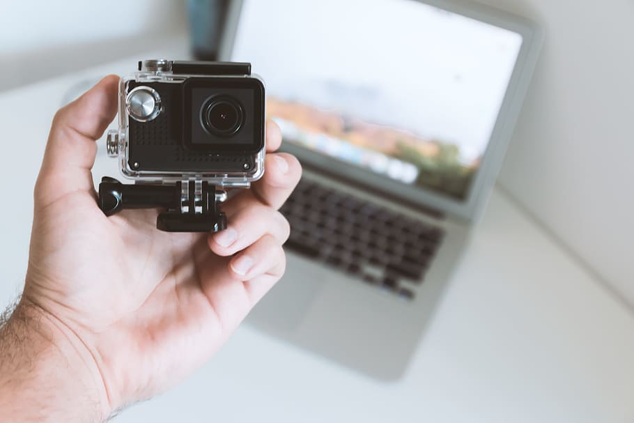 Modern small sport and outdoor camera in the hand of man at office HD wallpaper