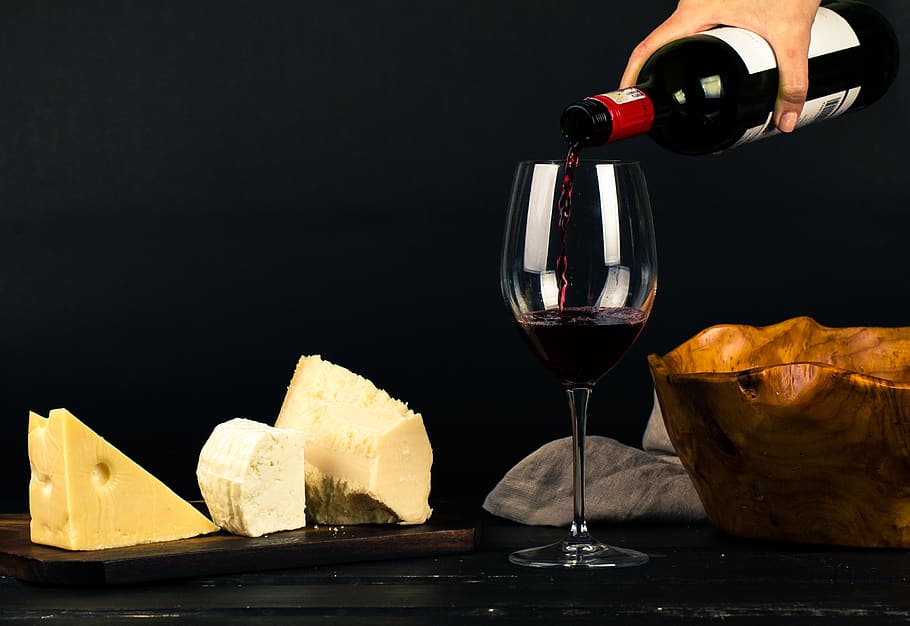 Photo of Person Pouring Wine into Glass besides Some Cheese Pairings HD wallpaper
