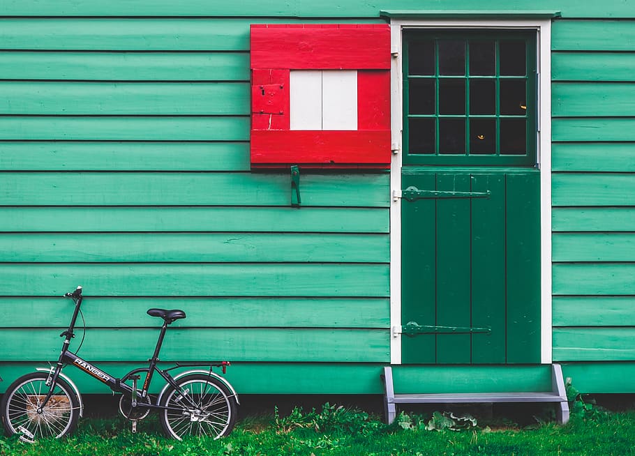 black folding bicycle leaning beside green house, vehicle, bike