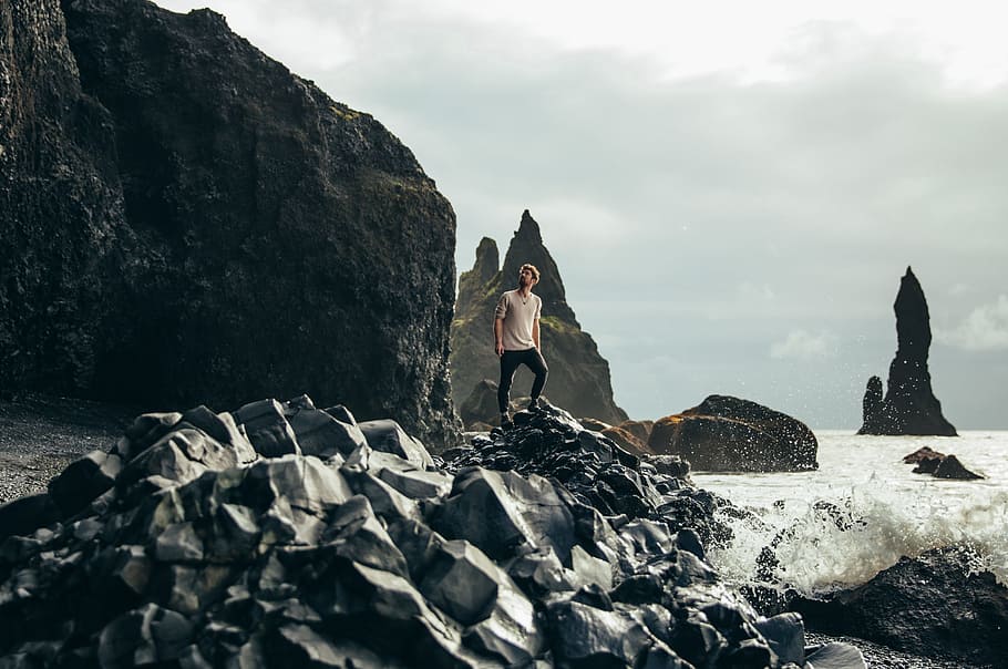 A young caucasian hiker on volcanic rocks by the sea, 25-30 year old