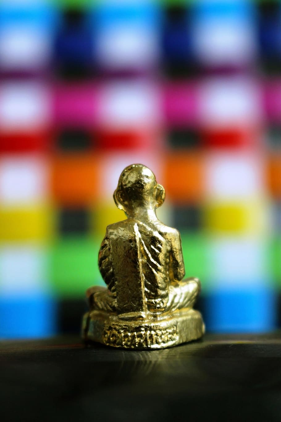 Back view of a golden Buddha statue isolated against a bright multi colored checked background