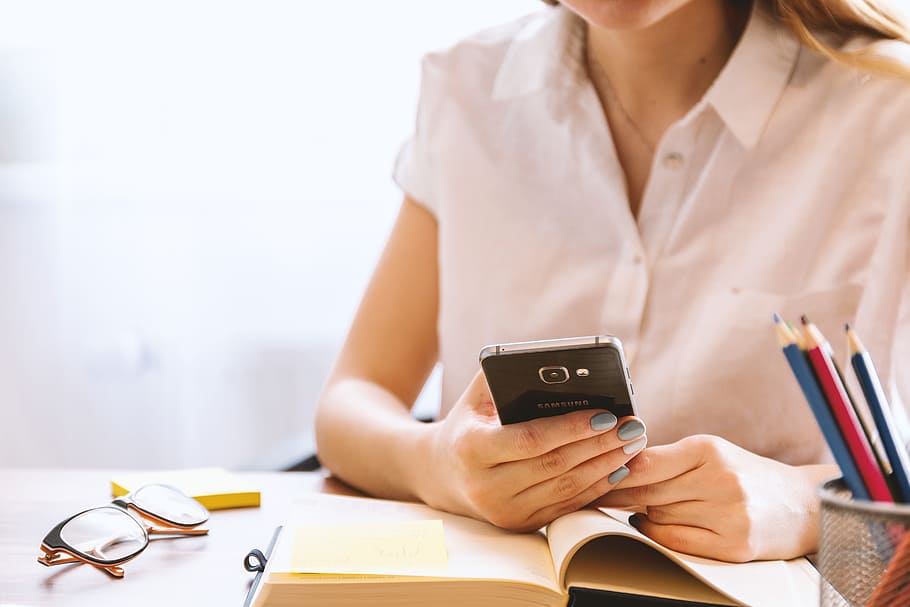 Young woman uses smartphone at the office, holding, one person HD wallpaper