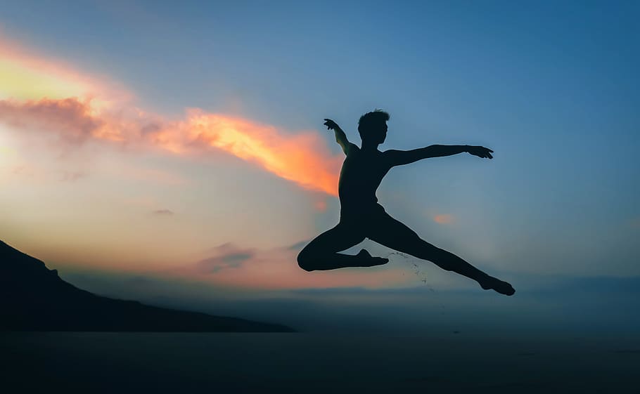 silhouette of man jumping doing ballet dance under golden hour