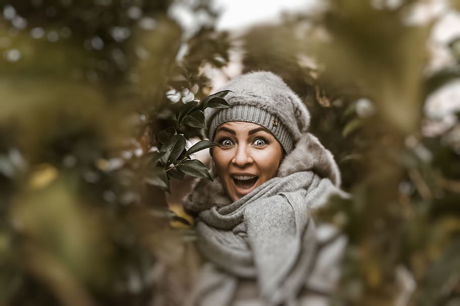 Smiling Woman Wearing Grey Coat and Cap Beside Green Plants, action HD wallpaper