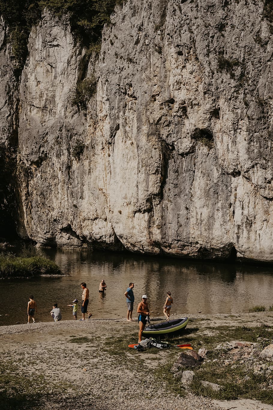 people bathing at river by the rock wall cliff, human, person