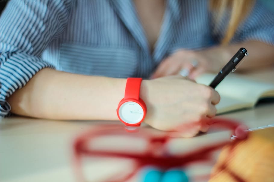 person wearing red analog watch holding twist pen, human, hand