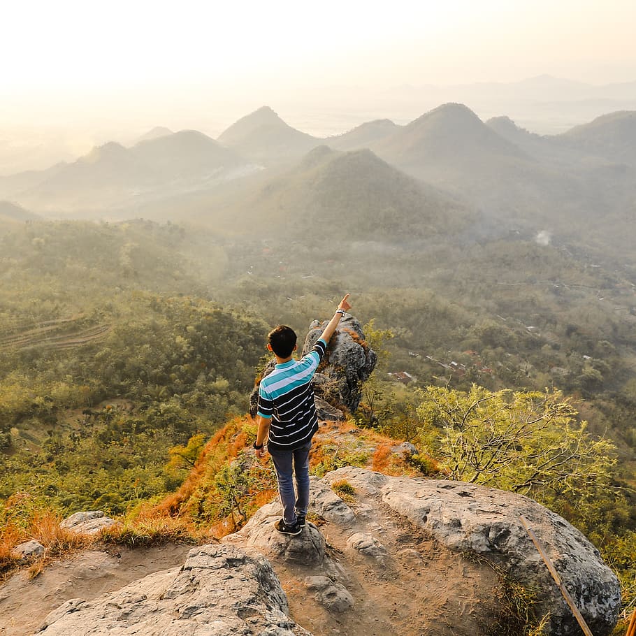 Photo of Man Standing on Rock Mountain Pointing Out Mountain HD wallpaper