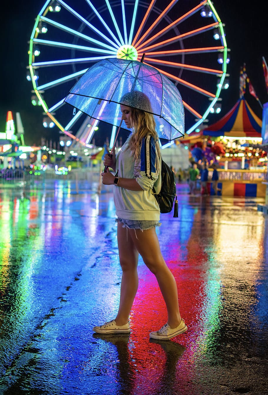 woman walking on pavement holding umbrella, carnival, night, neon