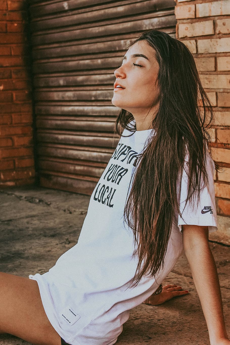 woman wearing white and black shirt sitting on gray concrete HD wallpaper