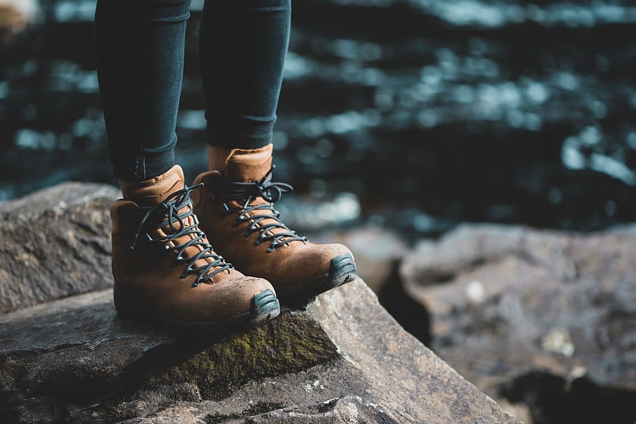 person wearing brown boots standing on rock, nature, ocean, water