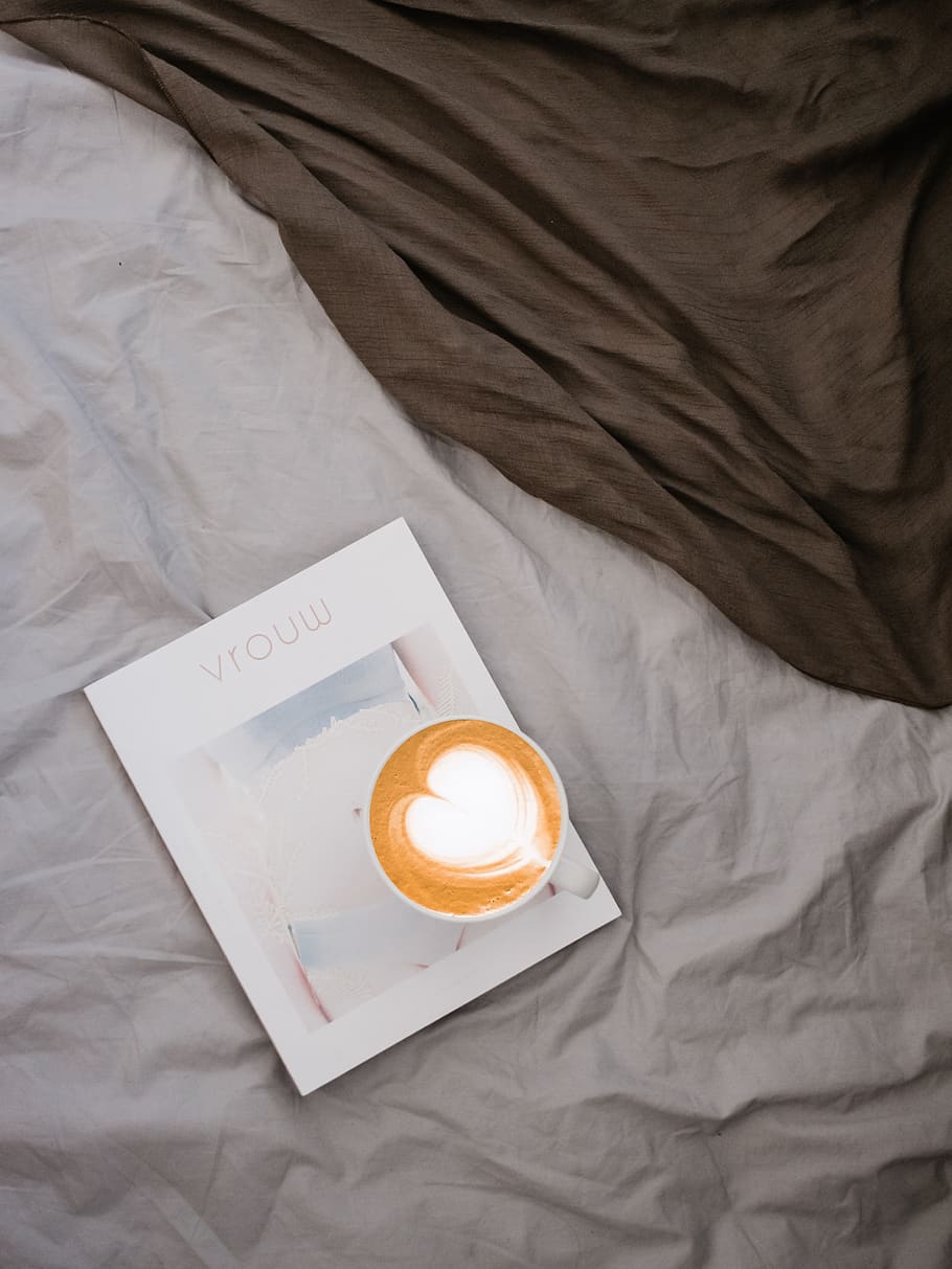 white ceramic cup on white labeled book, bed, indoors, high angle view HD wallpaper