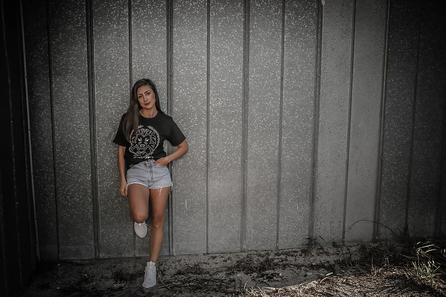 Woman Wearing Black Shirt and Daisy Dukes Leaning on Wall, attractive