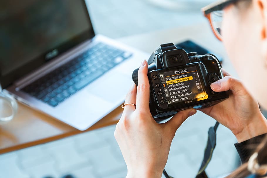 Photographer changes settings his DSLR camera at the modern office HD wallpaper