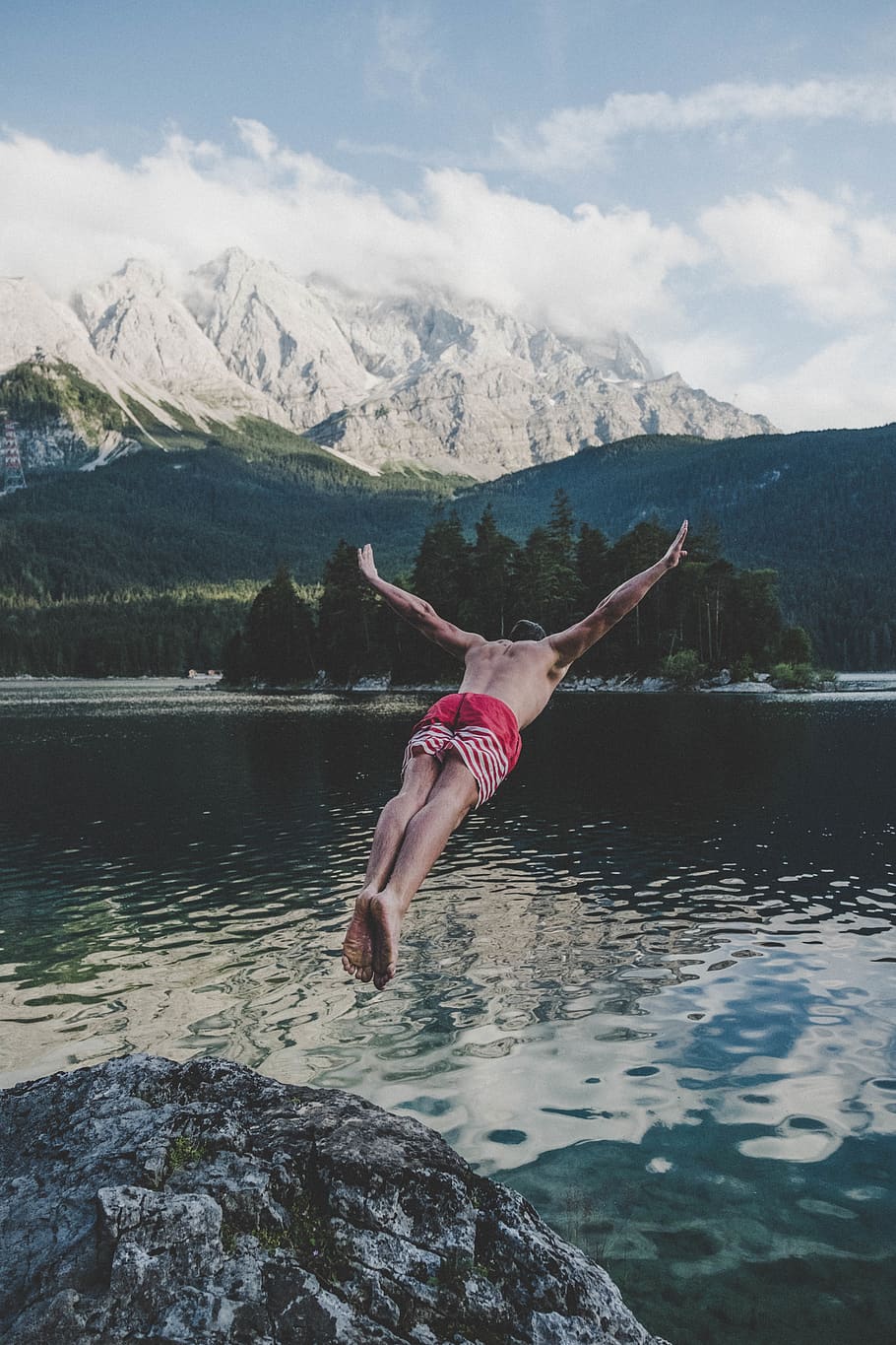 Man Wearing Red and White Striped Shorts Diving from Brown Rock HD wallpaper