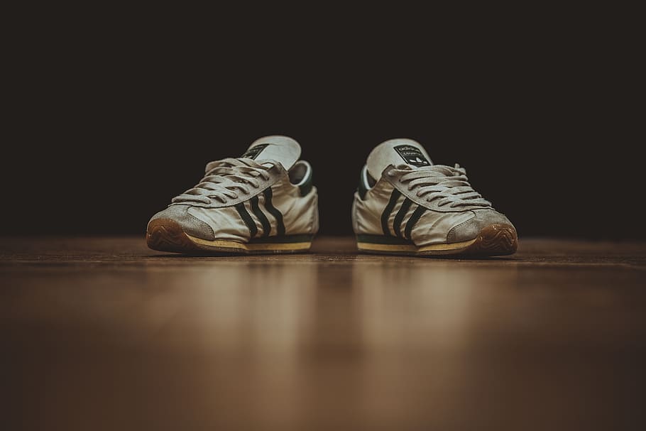 pair of gray adidas low-top sneakers on brown wood, feet, shoe