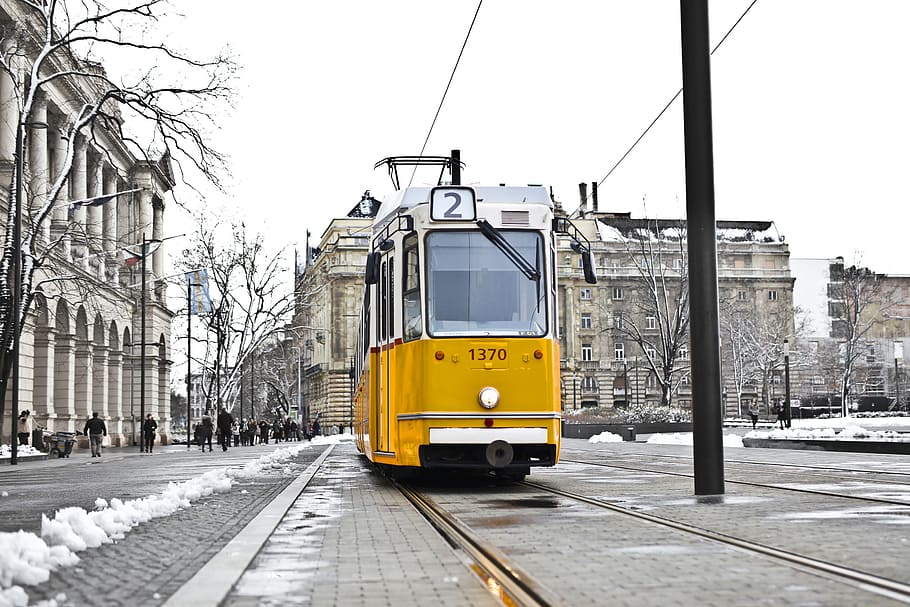 A yellow tram on a snowy road during the day time, cityscape