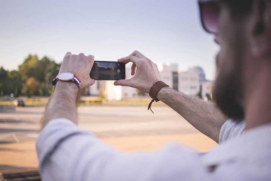 Tilt Shift Photo of Man Holding Black Smartphone Taking Photo of Gray Ground at Daytime HD wallpaper