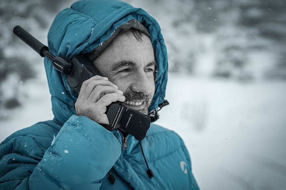 Man in Blue Hoodie Jacket Holding Black Radio Receiver during Snowy Day Time HD wallpaper