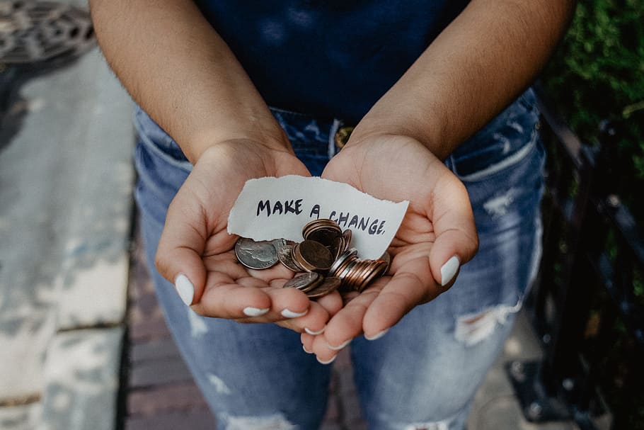 person showing both hands with make a change note and coins, money
