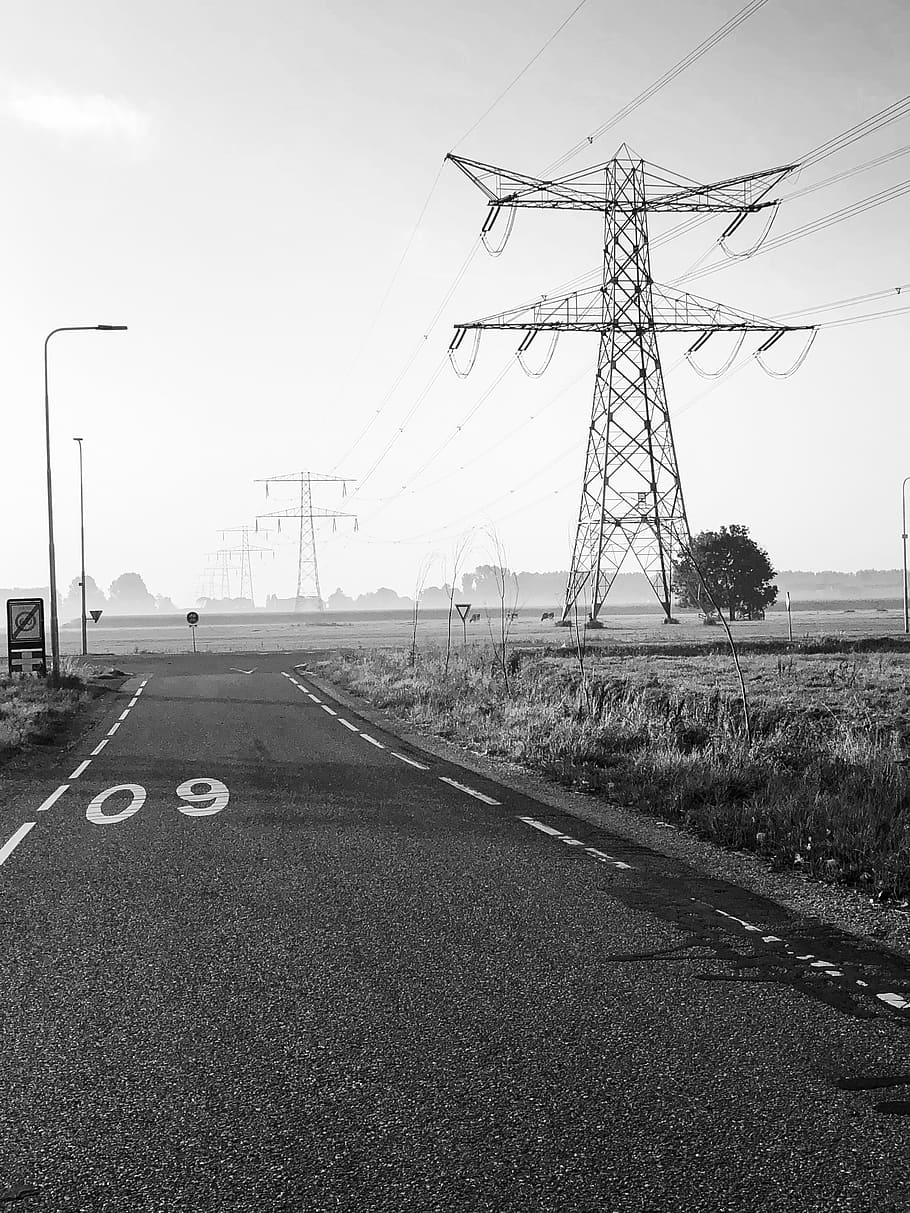 grayscale photography of road with utility tower, highway, tree