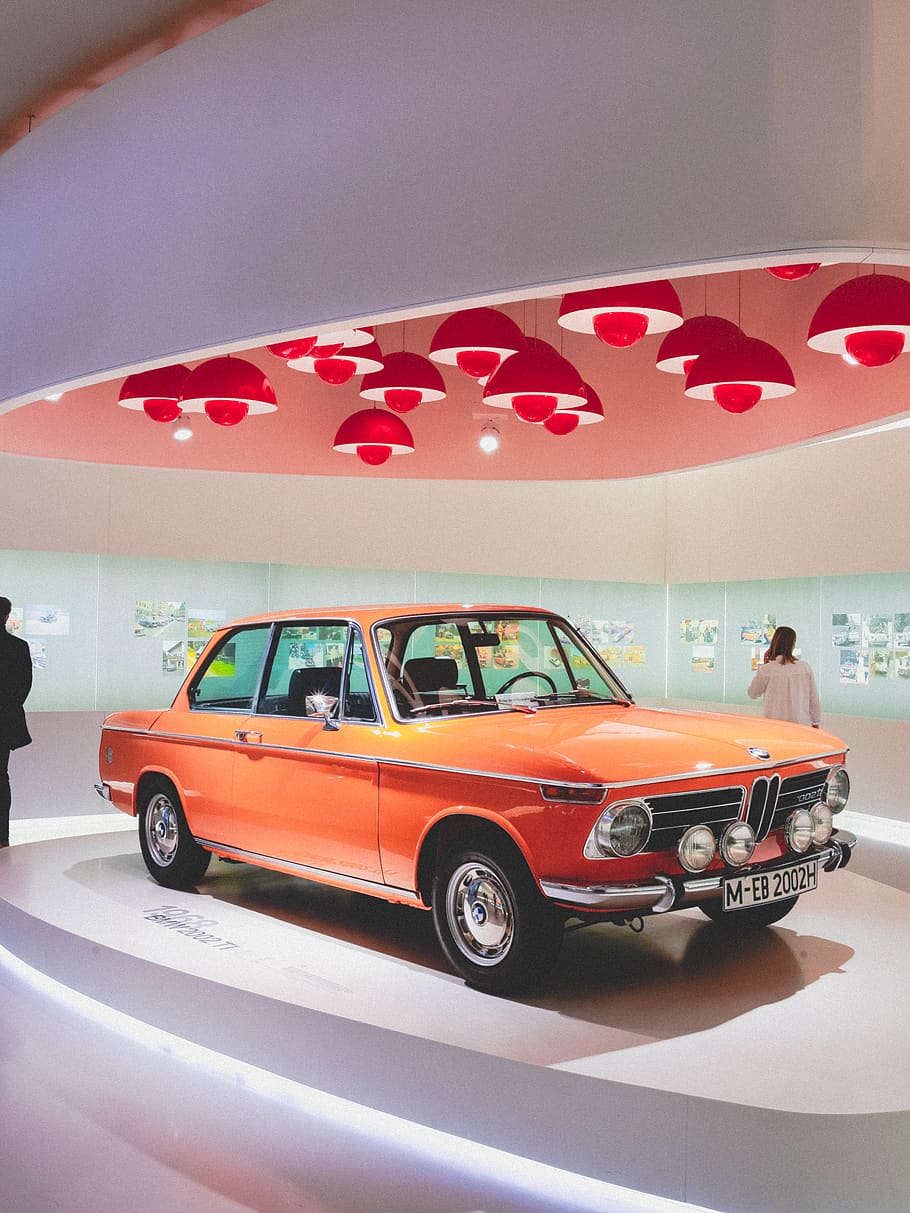 orange coupe on display area, car, vehicle, munich, germany, sedan HD wallpaper