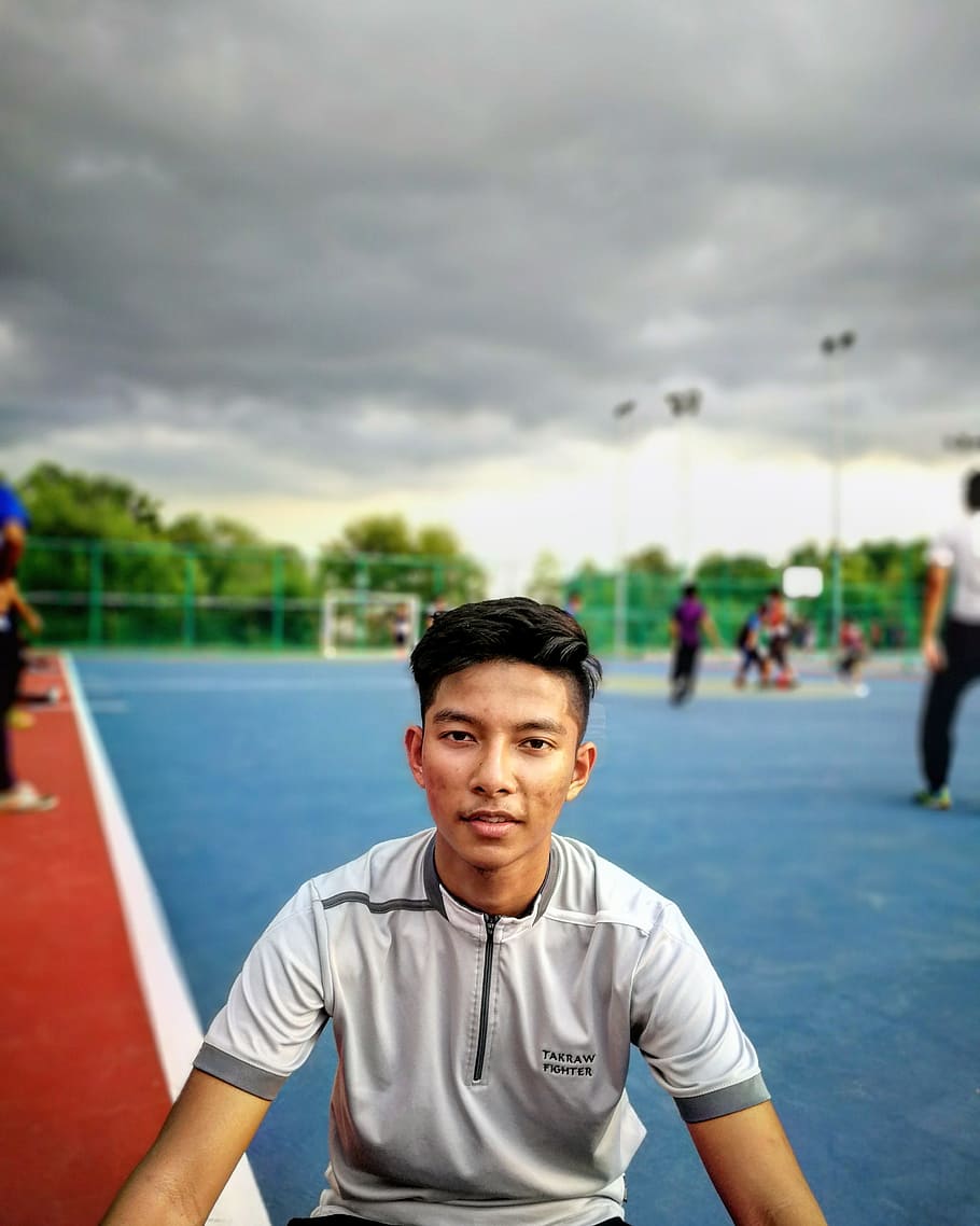 Tilt Lens Photography of Man Sitting Near Soccer Field during Cloudy Day HD wallpaper