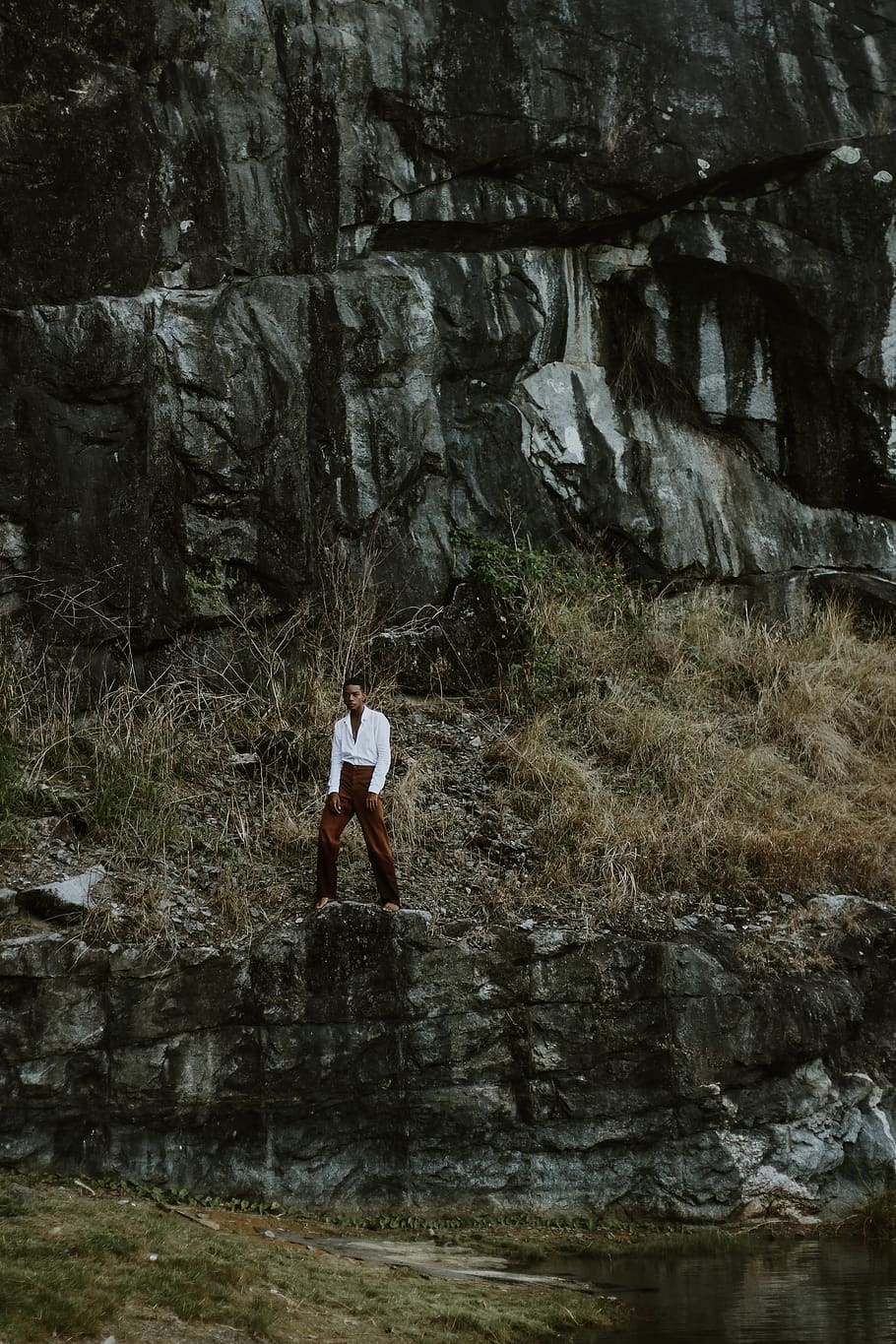 Man in White Long-sleeved Shirt and Maroon Pants Standing Near Cliff HD wallpaper