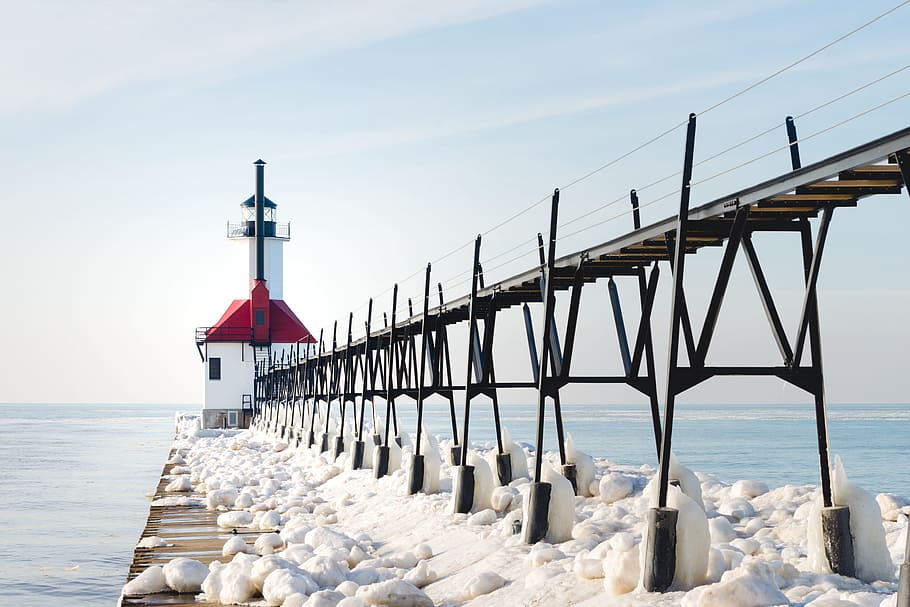 Red and White Concrete Lighthouse Surrounded by Snow Near Body of Water HD wallpaper