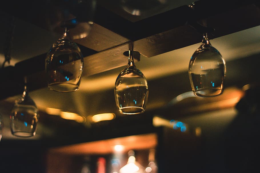 Selective Focus Photography of Wine Glass Hanging on Black Wooden Rack HD wallpaper