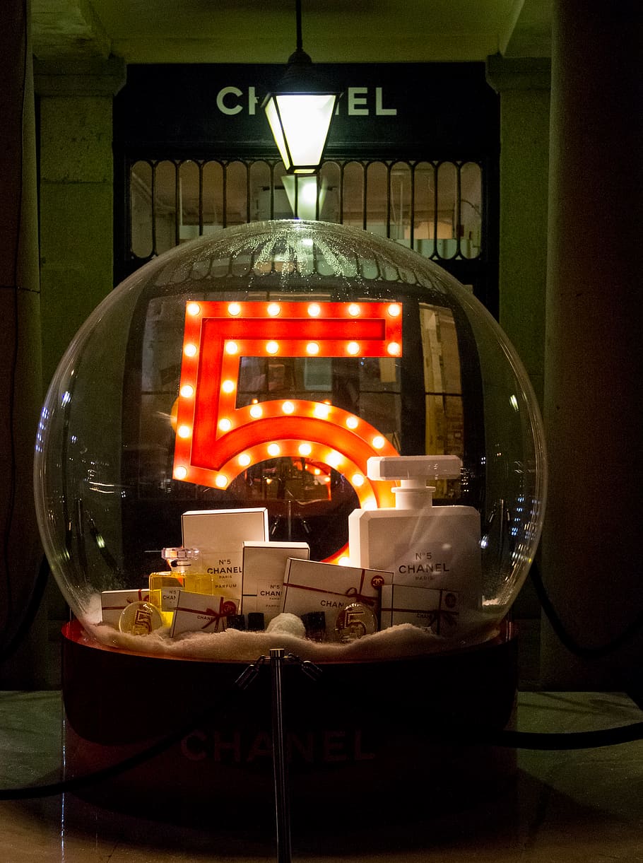 A large glass ball with the number 5, full of Chanel products in front of their storefront.