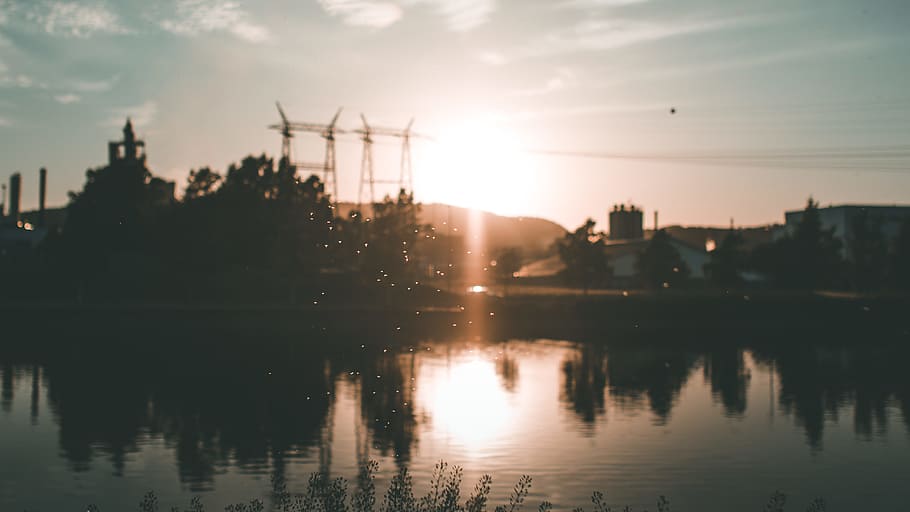 Silhouette of Building and Trees Near Body of Water during Golden Hour HD wallpaper